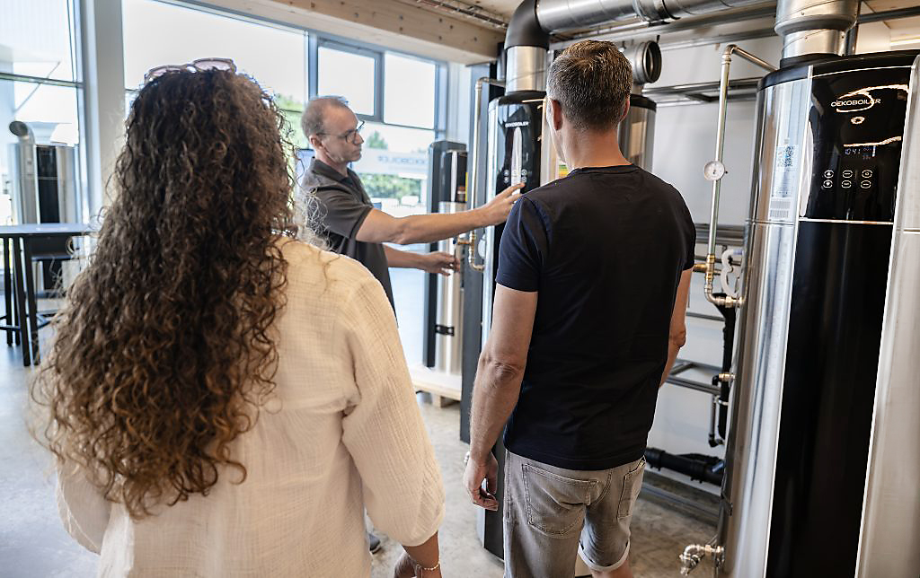 Fachperson erklärt zwei Kundinnen und Kunden einen Oekoboiler Wärmepumpenboiler